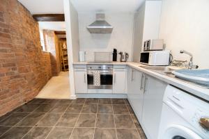 a kitchen with white appliances and a brick wall at Rustic 2BR Loft Exposed Brick & Beams in Liverpool