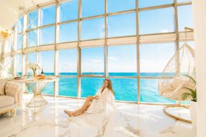 a woman sitting in a room with a view of the ocean at Penthouse Panorama Luxury Sea View Premium Stay in Batumi in Batumi