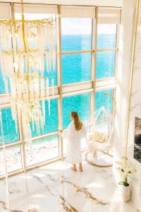 a woman in a white robe looking out of a window at the ocean at Penthouse Panorama Luxury Sea View Premium Stay in Batumi in Batumi