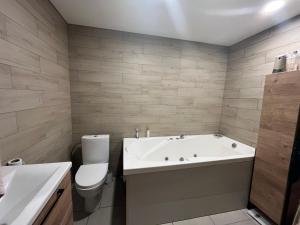 a bathroom with a tub and a toilet and a sink at Bebro namai in Vilnius