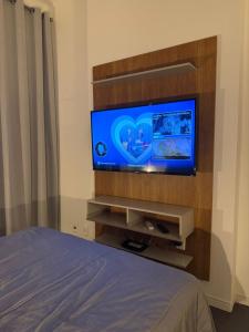 a flat screen tv in a bedroom with a bed at Studio Industrial in Niterói