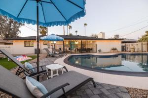 a swimming pool with chairs and a blue umbrella at Tempe Wesleyan in Tempe