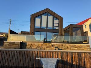 a house with glass windows and a white chair at OceanView Karmoy Jacuzzi, Sauna & Sea Views in Karmøy +31 photos