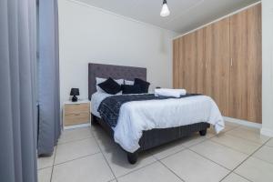 a bedroom with a bed and a wooden cabinet at Fynbos Lifestyle Estate - One Bed Apartment in Cape Town +5 photos