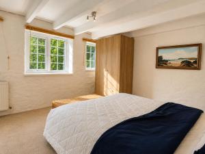 a bedroom with a large bed and two windows at Holiday Cottage Falmouth in Penryn