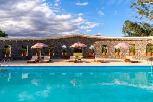 a pool with chairs and umbrellas next to a building at Finca El Recreo in Cafayate