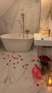 a bathroom with a tub and a sink and flowers on the floor at Eden Apartament Jakuzzi, sauna in Rozewie +11 photos