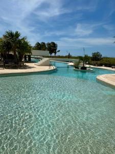 ein großer Pool mit blauem Wasser und Palmen in der Unterkunft Telchac Ocean Suite in Xtampú
