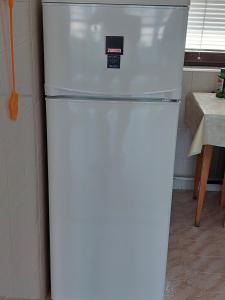 a white refrigerator in a kitchen next to a table at Pagoda Vendégház in Hajdúdorog