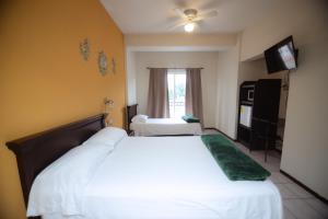 ein Hotelzimmer mit einem weißen Bett und einem Fernseher in der Unterkunft Nova Departamentos in Cadereyta Jiménez