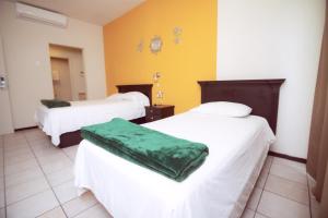 ein Zimmer mit zwei Betten mit weißen Laken und einem grünen Kissen in der Unterkunft Nova Departamentos in Cadereyta Jiménez