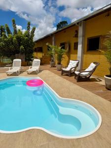 a swimming pool with two chairs and a house at The Barn Experience - Mantiqueira in Sylvestre Ferraz