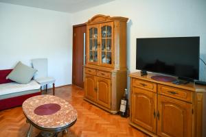 a living room with a television and a wooden cabinet at Apartmani Andjelka in Tivat