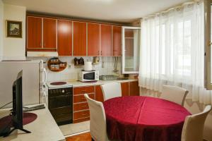 a kitchen with a table with a red table cloth at Apartmani Andjelka in Tivat