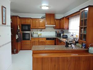 a kitchen with wooden cabinets and a counter top at Great for Families in Lourinhã-Double Rooms-Private Baths-Free Parking & Extra Bed in Lourinhã