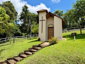 a small chapel in the grass with a cross on the door at The Barn Experience - Mantiqueira in Sylvestre Ferraz +19 photos