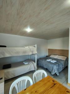 a bedroom with two beds and a table and chairs at Hospedaje Diente de Leon in Ataliva Roca