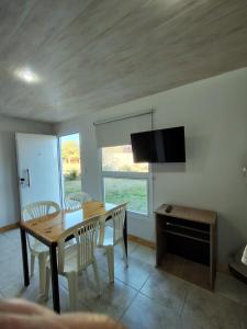 a dining room with a table and chairs and a television at Hospedaje Diente de Leon in Ataliva Roca