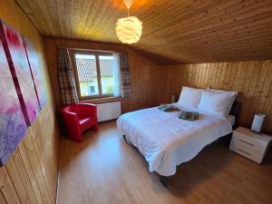 a bedroom with a bed and a red chair at Swiss Chalet direkt am Thunersee in Thun