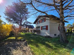 a white house with a tree in the yard at Swiss Chalet direkt am Thunersee in Thun