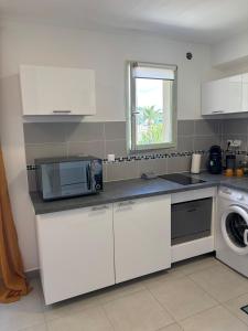 a kitchen with white cabinets and a microwave and a window at Studio tout équipé centre Erbalunga in Brando