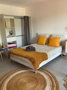 a bedroom with a bed with orange pillows and a rug at Studio tout équipé centre Erbalunga in Brando