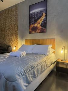 a bedroom with a large bed with a picture on the wall at Studio Industrial in Niterói