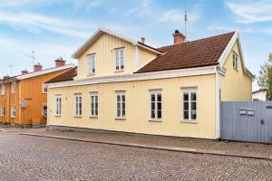 a yellow house with a brown roof on a street at Storgatan 30 i centrala Vimmerby in Vimmerby
