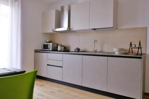 a kitchen with white cabinets and a green chair at Le Mele - Alle 5 Torri in Mezzolombardo