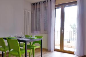 a dining room with a table and green chairs at Le Mele - Alle 5 Torri in Mezzolombardo