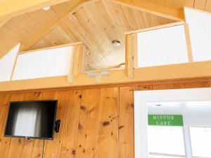 a tiny house with a tv on the wall at Cottage 12 - King Bed Child Loft w Twin Private Bath Kitchenette Pets Allowed Fee applies in Wolfeboro