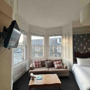 a living room with a couch and a bed and windows at Neidpath inn in Peebles +11 photos