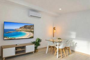 a dining room with a table and a tv on the wall at Deluxe Arguineguin Beach in Arguineguín