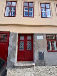 a red door of a building with four windows at Podkrovní Apartmán in Třebíč