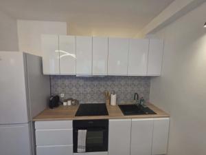 a kitchen with white cabinets and a sink and a refrigerator at Apartament Anny 1 in Grodzisk Mazowiecki +2 photos