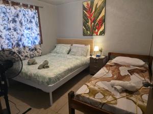 a bedroom with two beds and a fan and a window at G&A Friendly stay in Port Vila +8 photos