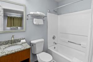 a bathroom with a toilet and a sink and a mirror at HomeTowne Studios by Red Roof Orlando South in Orlando +23 photos