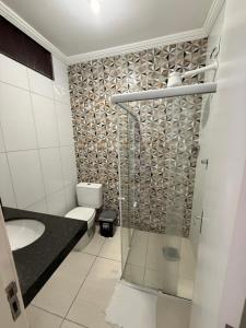 a bathroom with a toilet and a glass shower at Pousada canto do forte in Cabo Frio