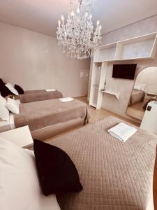 a bedroom with two beds and a chandelier at POUSADA DONATELLA Modernidade e conforto para noites tranquilas in Paranaguá