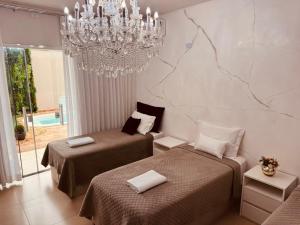 a bedroom with two beds and a chandelier at POUSADA DONATELLA Modernidade e conforto para noites tranquilas in Paranaguá
