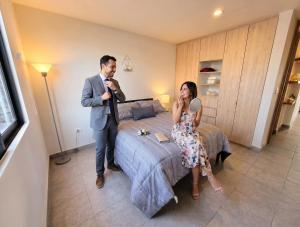 a man and a woman standing next to a bed at Luminoso departamento cerca de bodas y jardines! in Atlixco