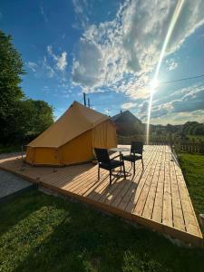 a tent with two chairs and a table on a wooden deck at Ardennes Prestige Glamping in La Neuville-aux-Joûtes