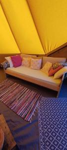 a couch with pillows on it in a tent at Ardennes Prestige Glamping in La Neuville-aux-Joûtes