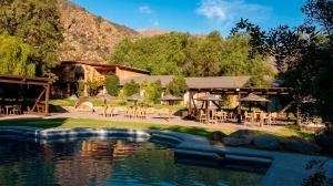 a resort with a pool of water with tables and chairs at Casa Bosque Lodge in San José de Maipo