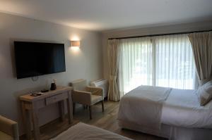 a hotel room with a bed and a desk and a television at Casa Bosque Lodge in San José de Maipo
