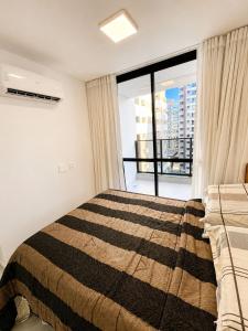 a bedroom with a bed and a large window at SkyHero Apê in Vila Velha