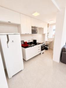 a kitchen with white cabinets and a white refrigerator at SkyHero Apê in Vila Velha