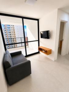 a living room with a couch and a large window at SkyHero Apê in Vila Velha