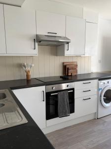 a kitchen with white cabinets and a washer and dryer at One bedroom flat in Pevensey Bay in Pevensey +11 photos