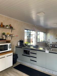 a large kitchen with white cabinets and a sink at Pousada Pé da Serra - Rio do Rastro in Lauro Müller